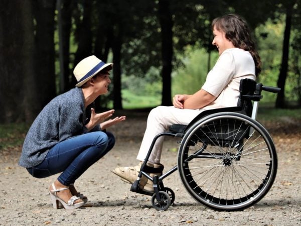 woman in wheelchair laughing with woman crouching