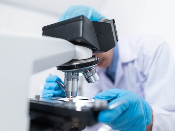 medical technician using microscope